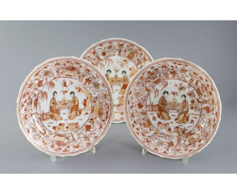 A set of three Chinese rouge de fer moulded dishes, Kangxi period, each painted with two ladies seated in a garden and playin