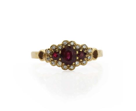 An 18ct gold ruby and diamond cluster ring, a central claw set oval mixed cut ruby flanked by a circular cut ruby on each sid