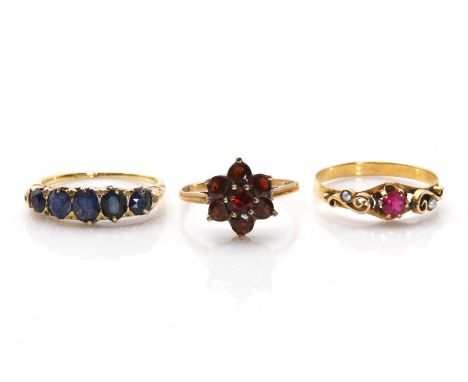 Three gold rings, comprising a five stone sapphire ring, with graduated oval mixed cut sapphires, claw set to a scrolling Edw