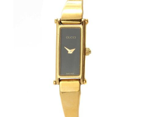A ladies' gold plated Gucci quartz bangle watch, a rectangular case with a black dial, signed Gucci, to tapering bangle termi
