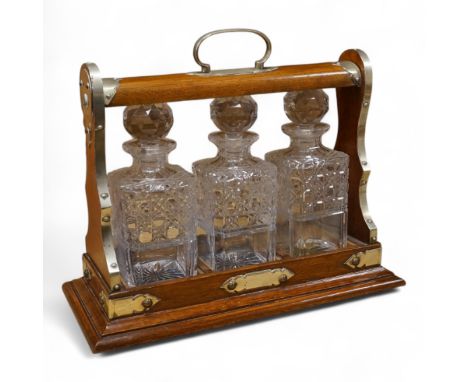 An oak and brass three bottle tantalus, 40cm wide, no key