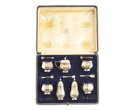 A George V seven-piece silver condiment set, of octagonal shape, blue glass liners, pepperettes 90mm h, by The Goldsmiths &am