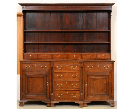 A George III oak dresser, North Wales, the three shelf boarded rack with stepped cornice and shaped sides, fitted with row of