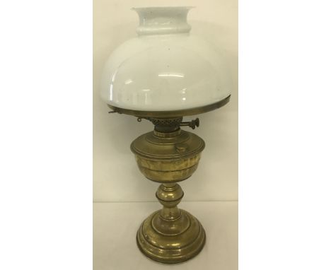 A vintage brass oil lamp with white glass shade and glass chimney.  