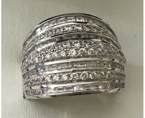 A large 925 silver ladies band style dress ring set with clear stones. Alternating bands of oblong cut and round cut stones. 