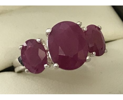 A 925 silver trilogy dress ring set with 3 rubies. Central stone 10mm x 7mm, stones each side 6mm x 4mm. Size K1/2.