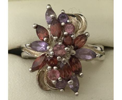 A 925 silver dress ring with unusual floral amethyst, garnet and pink topaz set design.  Size O.