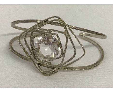 A unusual design bangle style bracelet. Set with large clear stone surrounded by off set squares. Marked 925.