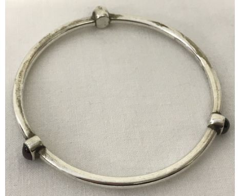 A 925 silver bangle with 3 bezel set garnet cabochons.  