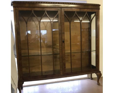 A vintage feather banded 2 door glass display cabinet with cabriole style legs. Complete with key and a glass interior shelf.