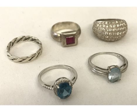 5 silver dress rings. 4 stone set. A silver twisted band, a crystal set dome band ring, a central blue topaz stone set ring, 