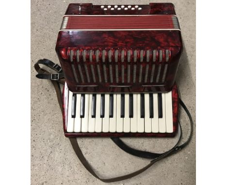 A vintage German red and black pearlised design accordion. In good playable condition, one rubber foot is loose. 
