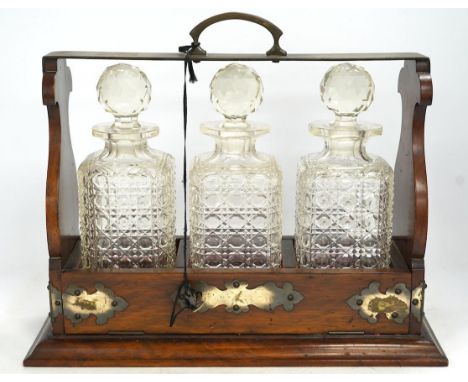 A three bottle tantalus with key, 38cm wide. Condition - fair, chipping to the stoppers