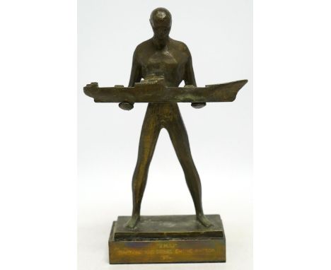 A 1960s modernist bronze figure of a man holding a boat, plaque inscribed ‘“3.MAJ” SHIPYARD AND DIESEL ENGINE FACTORY 1968.’,