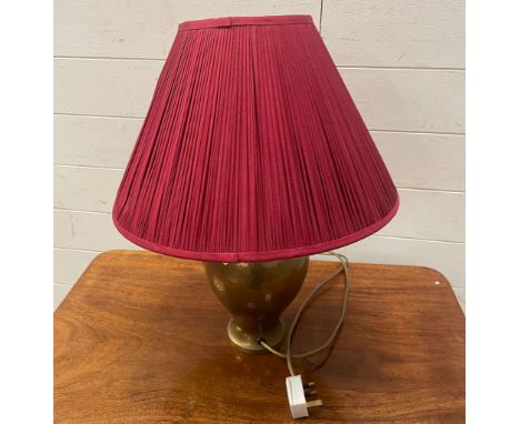 A brass table lamp with red shade 