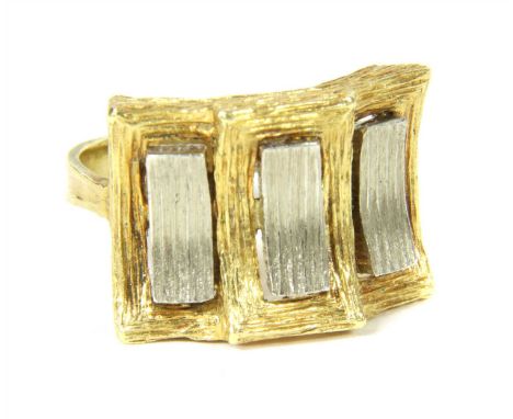 A 1970s 18ct two colour gold dress ring, the stepped head with three raised white curved rectangles to yellow frame, textured