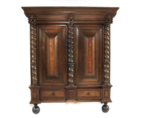 A large Dutch oak cupboard, 17th century style, the swept cornice above a moulded frieze, set with carved lion masks, bearing