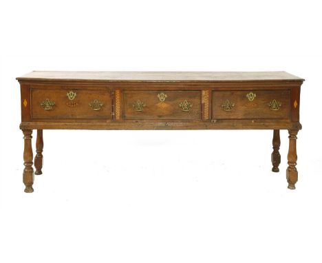 A three-drawer oak dresser base, early 18th century, on ring-turned legs, 210cm wide, 50cm deep, 80cm high