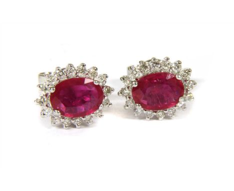 A pair of white gold ruby and diamond cluster stud earrings, an oval mixed cut ruby, possibly fracture filled , four claw set