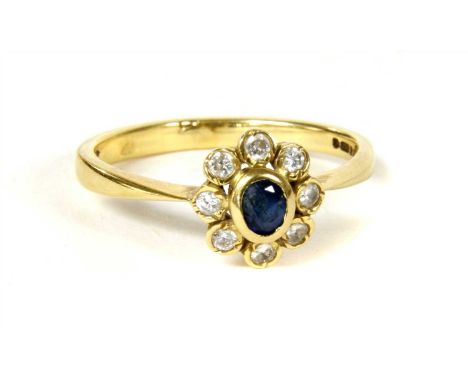 An 18ct gold sapphire and diamond cluster ring, with an oval mixed cut sapphire rub set to the centre, to a border of rub set