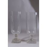 A PAIR OF GLASS HURRICANE LAMPS on square bases. 13ins high.