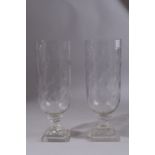 A PAIR OF GLASS HURRICANE LAMPS on square bases. 13ins high.