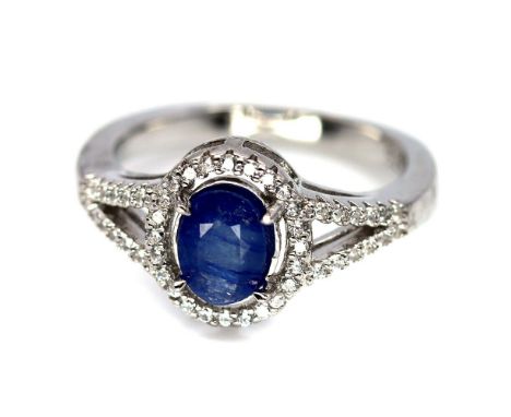 A 925 silver cluster ring set with an oval cut sapphire surrounded by white stones, (N).