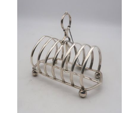 A Victorian silver six division toast rack, the ribs arched, with a loop carrying handle, on four ball feet, by Henry Wilkins