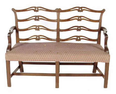 A George III mahogany double chair back settee, with a pierced ladder back carved with leaf scrolls with moulded and chamfere