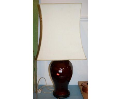 A large red glazed ceramic table lamp of baluster form with matching shade