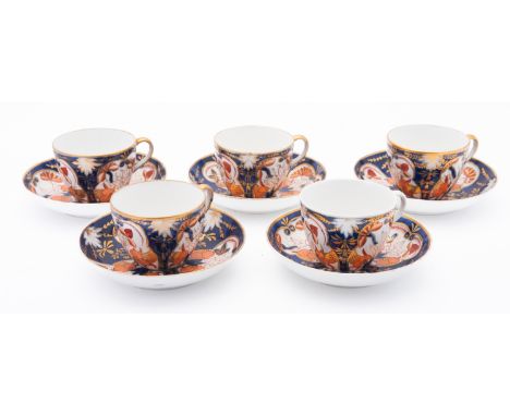 An Imari pattern set of five cups and saucers. Having floral decoration on a blue and white ground with gilt border.