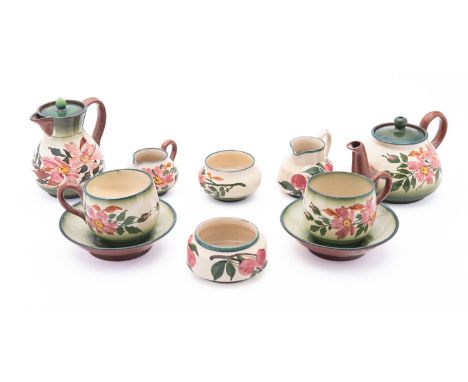 A Devon pottery part tea set, having floral decoration on a green ground, comprising a teapot, milk jug, two bowls, two small