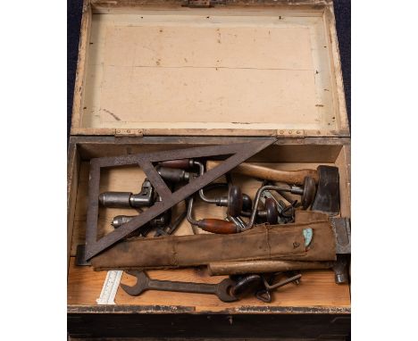 A collection of various woodworking tools, contained within a pine trunk including braces, awls, an auger etc.