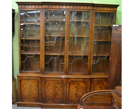 A reproduction Georgian style break front bookcase, with dentil and arcaded cornice over astragal glazed doors, the lower sec