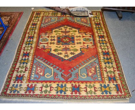 A Kazak rug, West Anatolia, the madder field with ivory panel enclosed by geometric borders, 190cm x 130cm