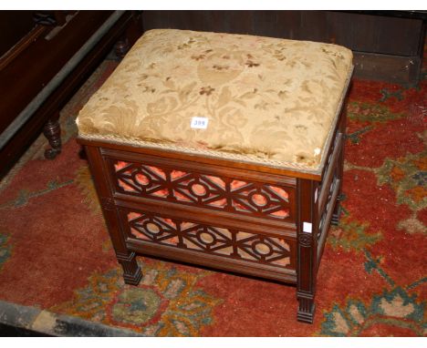 A late Victorian mahogany piano stool with a hinged upholstered seat and fret decoration to the sides 