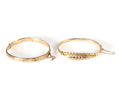 A late nineteenth century ruby bangle, graduated round cut rubies to a lozenge shaped plaque in a rope frame, to a plain hing