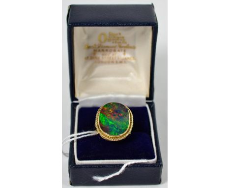 A 9 carat gold boulder opal ring, an oval cabochon opal in a rubbed over setting within a rope frame, to scroll shoulders, fi