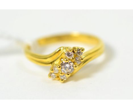 An 18 carat gold diamond ring, a round brilliant cut diamond spaced by clusters of smaller diamonds, to a bypass setting, tot