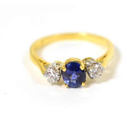 An 18 carat gold sapphire and diamond three stone ring, an oval cut sapphire in a claw setting, spaced by round brilliant cut