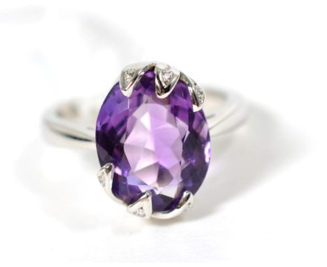 An 18 carat white gold amethyst and diamond ring, an oval cut amethyst in a fancy diamond set claw setting, finger size Q .  