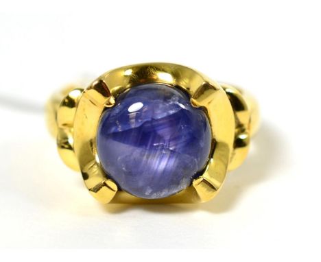 An 18 carat gold star sapphire ring, a circular star sapphire in an extended claw setting and circular frame, to a tapering s