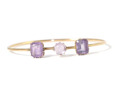 An early twentieth century amethyst bangle, a round cabochon amethyst spaced by two octagonal cut amethyst in claw settings, 