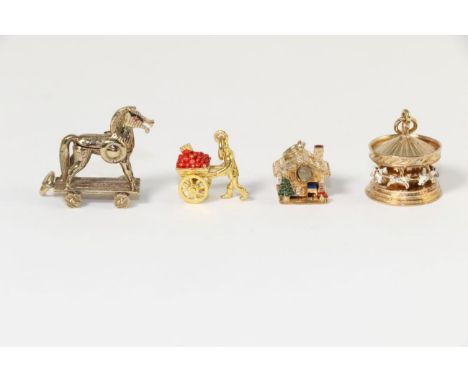 Four 9 carat gold and enamel charms, including; a carousel charm, a log cabin Stanhope viewer, an enamel apple cart and a Tro