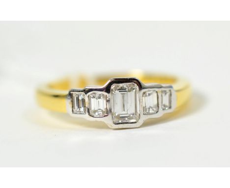 An 18 carat gold octagonal cut diamond ring, five graduated diamonds in rubbed over settings, to straight shoulders, total es