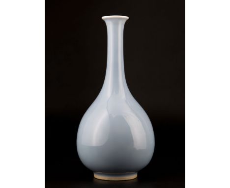  Shaped with a raised foot, an ovoid body and a long, narrow neck and flared rim, it is completely covered with a light blue