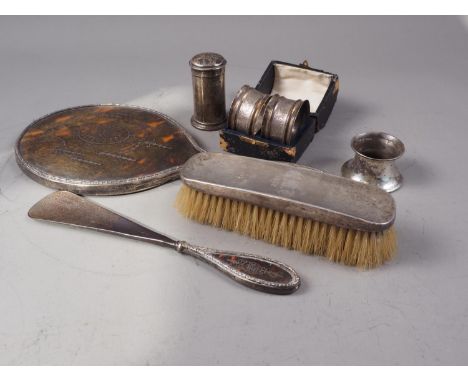 A tortoiseshell and silver mounted hand mirror, a matching shoe horn, a silver backed brush, a pepper pot, an inkwell stand a