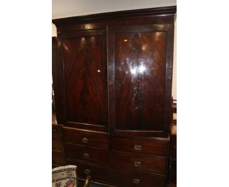 An early 19th century figured mahogany linen press, the upper section fitted trays enclosed two panelled doors over two short