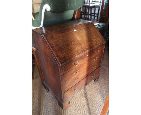 A late Georgian provincial oak fall front bureau with fitted interior drawers, pigeonholes and central cupboard over four lon