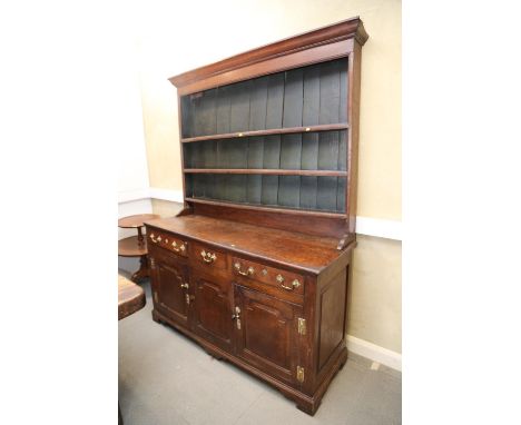 A George III oak dresser, fitted shelves over three drawers and two cupboards enclosed arched panel doors, on bracket feet, 6